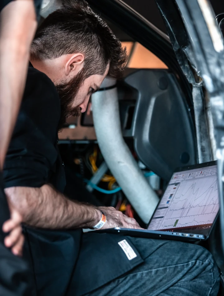 A man working with a laptop on a race car